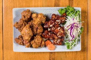 Appetizing crispy and glazed chicken with fresh vegetables on a plate.